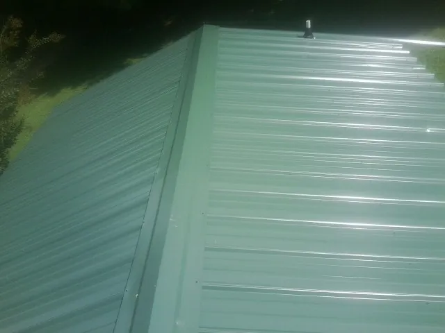 New green metal panels meeting at the ridge of a roof — Flat Roof Repair work by our crew in Manilla