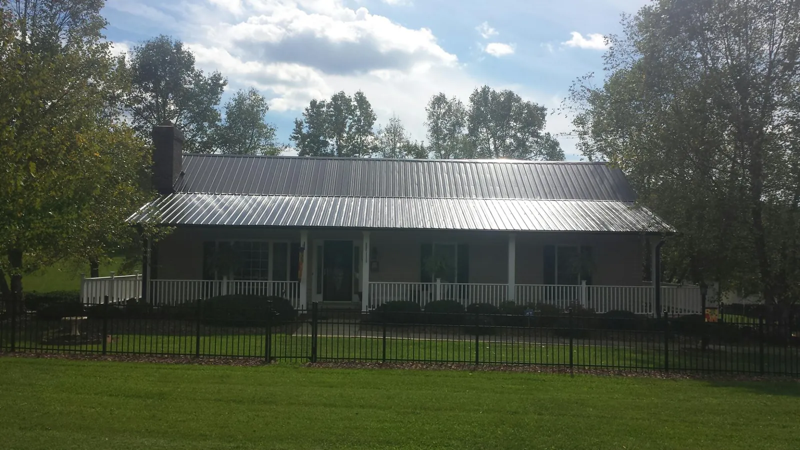 Gray metal roof on a brick ranch with a full width front porch — Gutter Guard Installation work by our crew in Manilla